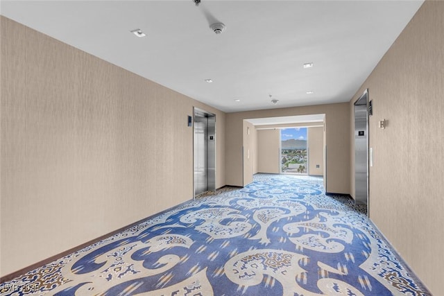 hallway with elevator and light carpet