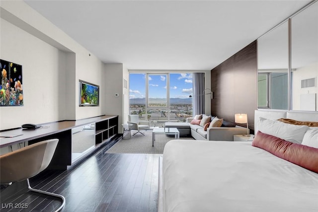 bedroom featuring expansive windows and dark wood-style floors