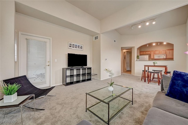 living area featuring vaulted ceiling, light colored carpet, baseboards, and visible vents