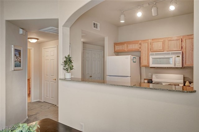 kitchen with light brown cabinets, visible vents, light stone countertops, arched walkways, and white appliances