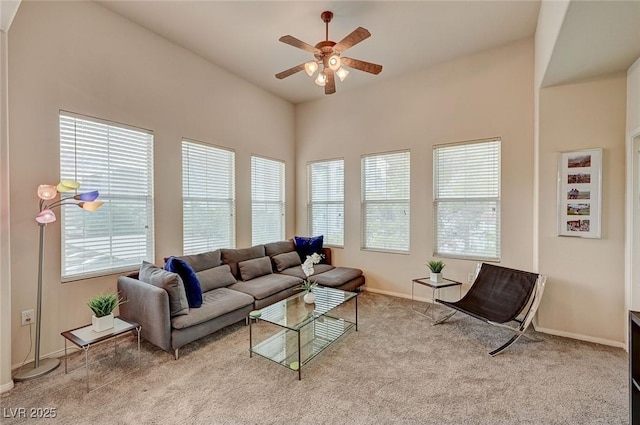 living area with carpet, baseboards, a ceiling fan, and a healthy amount of sunlight