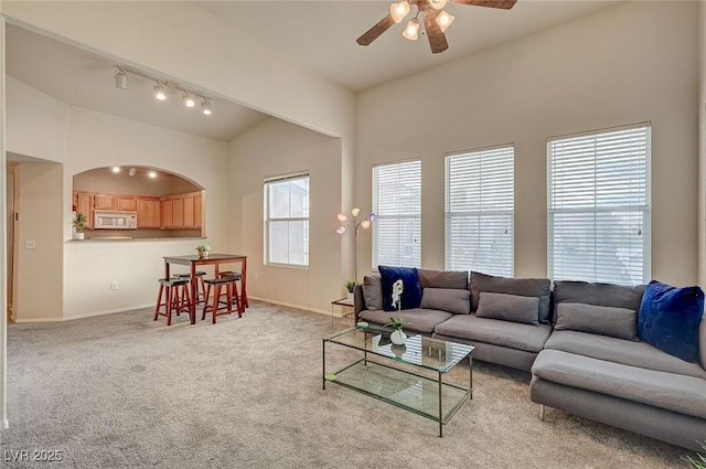 carpeted living area featuring baseboards, lofted ceiling, ceiling fan, and track lighting