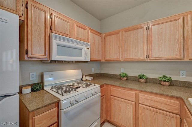 kitchen featuring light brown cabinetry and white appliances