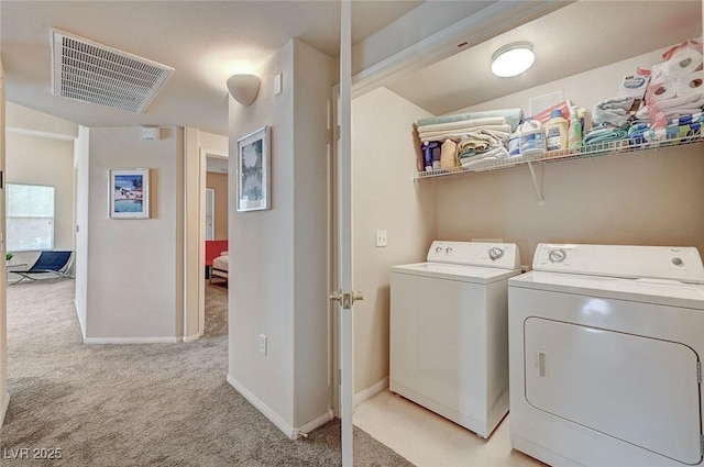 washroom featuring washer and clothes dryer, light colored carpet, baseboards, and visible vents