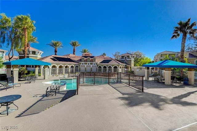 community pool with a patio area and fence