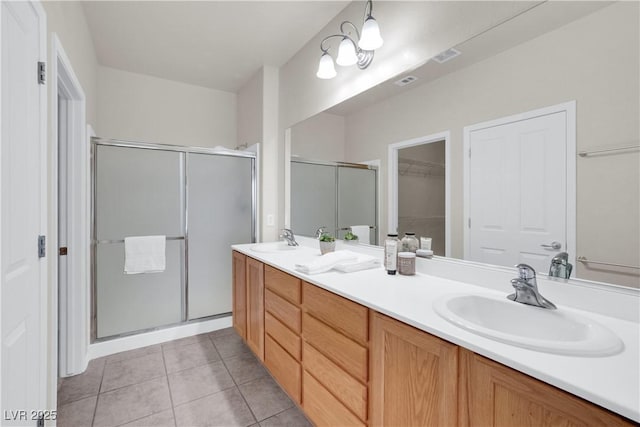 bathroom with a sink, double vanity, a stall shower, and tile patterned floors