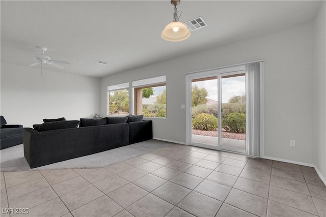 carpeted living area featuring ceiling fan, baseboards, visible vents, and tile patterned floors