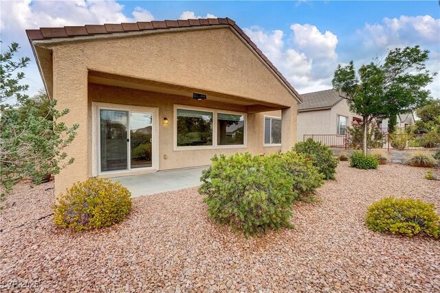 rear view of property with stucco siding, fence, and a patio