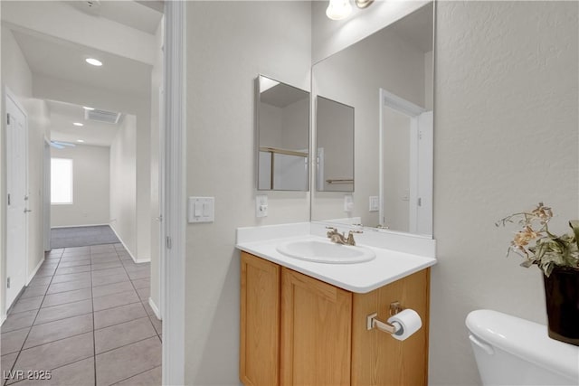 bathroom featuring toilet, visible vents, baseboards, tile patterned flooring, and vanity