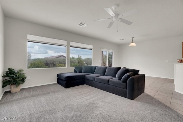 carpeted living area with visible vents, baseboards, a ceiling fan, and tile patterned flooring