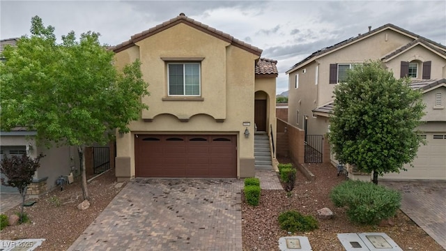 view of front of house with an attached garage, stucco siding, decorative driveway, and a tile roof