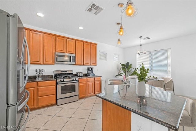 kitchen featuring appliances with stainless steel finishes, a sink, a chandelier, pendant lighting, and brown cabinets