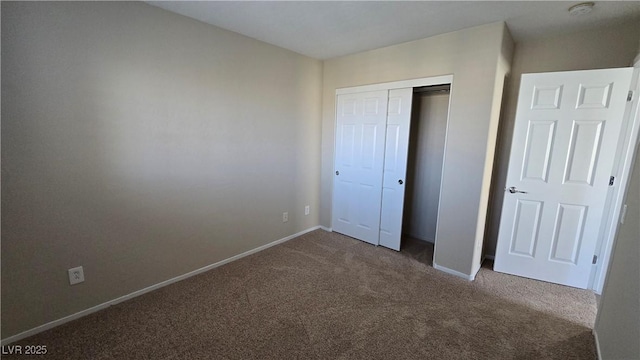 unfurnished bedroom with baseboards, carpet flooring, and a closet