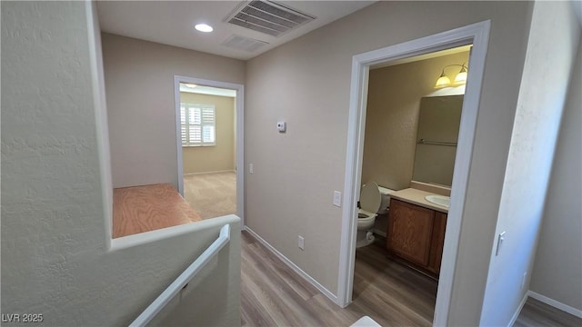 corridor featuring light wood finished floors, visible vents, and baseboards
