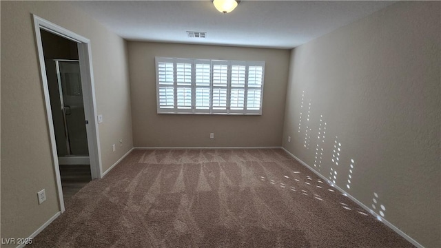 carpeted spare room featuring visible vents and baseboards