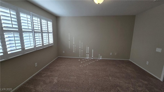 carpeted empty room featuring baseboards