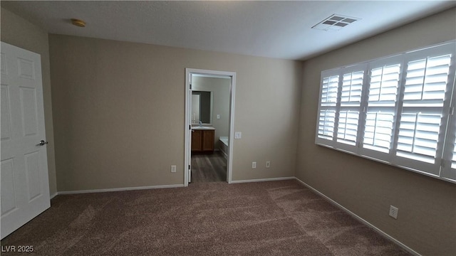 unfurnished bedroom featuring carpet, ensuite bathroom, visible vents, and baseboards