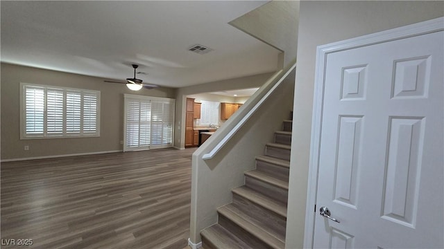 stairs featuring ceiling fan, baseboards, visible vents, and wood finished floors