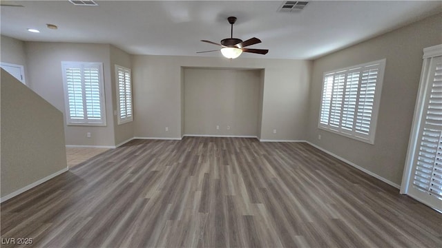 unfurnished living room with baseboards, a ceiling fan, visible vents, and wood finished floors