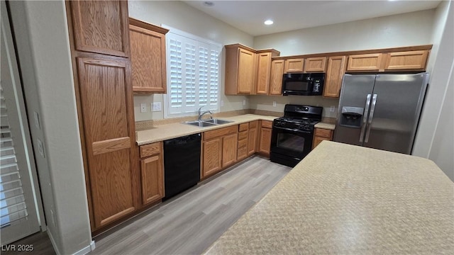 kitchen featuring a sink, black appliances, recessed lighting, light countertops, and light wood-style floors