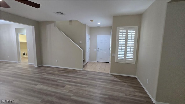 unfurnished living room featuring baseboards, visible vents, wood finished floors, and a ceiling fan