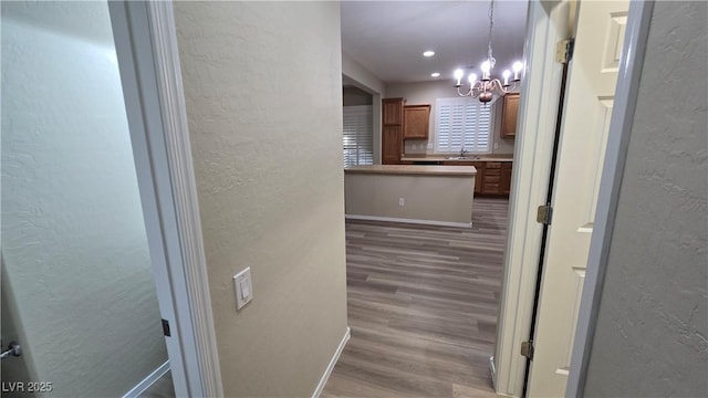 corridor featuring recessed lighting, a sink, a chandelier, wood finished floors, and a textured wall