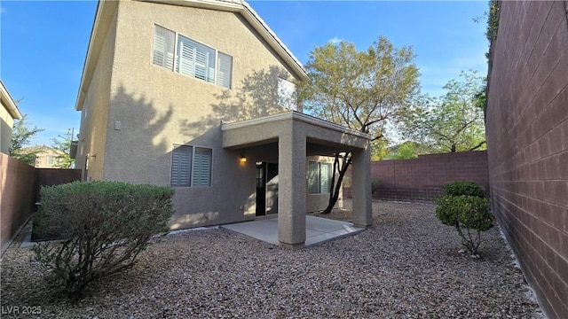 back of property with a patio area, stucco siding, and a fenced backyard