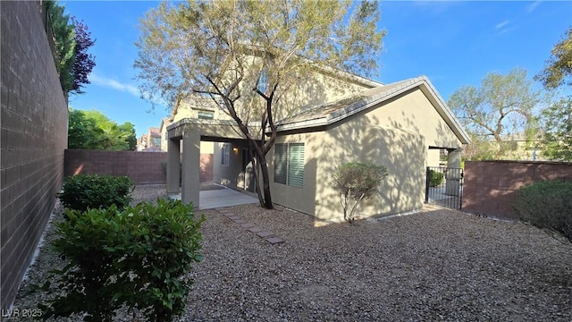 back of property featuring a fenced backyard, a patio, stucco siding, and a gate