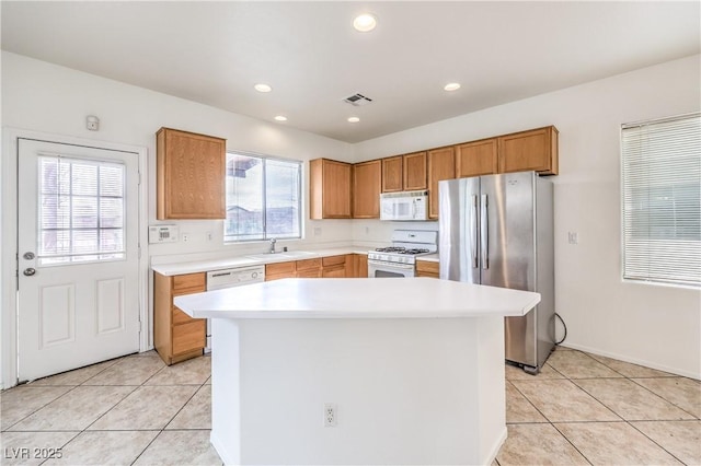 kitchen featuring a sink, white appliances, light countertops, and light tile patterned floors