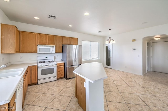 kitchen featuring a sink, white appliances, visible vents, light countertops, and a kitchen island