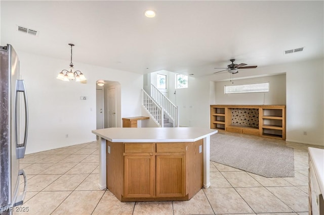 kitchen with freestanding refrigerator, visible vents, light tile patterned flooring, and ceiling fan with notable chandelier