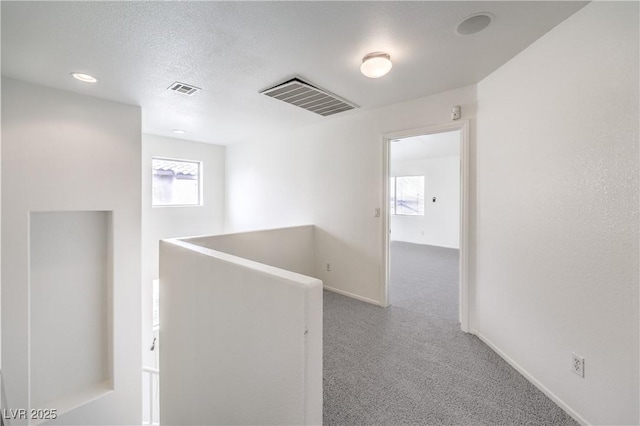 corridor featuring baseboards, carpet flooring, an upstairs landing, and visible vents