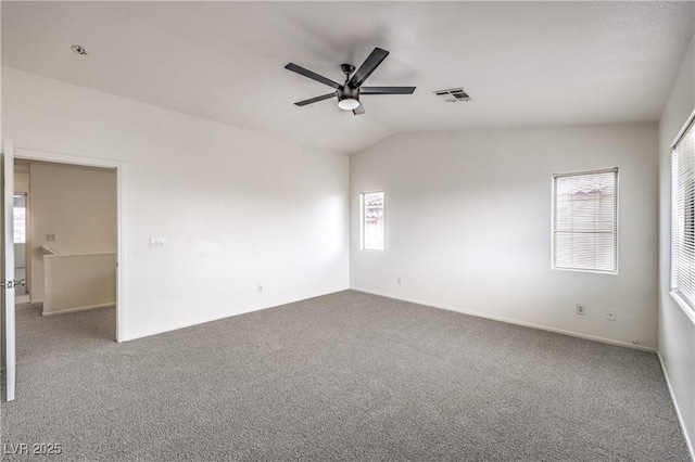 empty room with carpet flooring, visible vents, baseboards, ceiling fan, and lofted ceiling