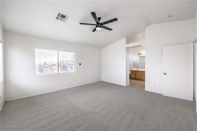 unfurnished bedroom with connected bathroom, a ceiling fan, visible vents, light colored carpet, and vaulted ceiling