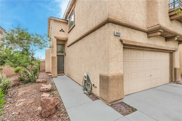 view of property exterior with fence, a garage, and stucco siding
