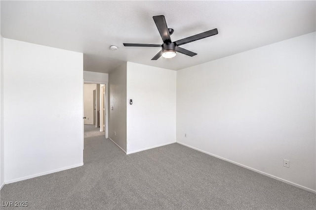 carpeted spare room featuring ceiling fan and baseboards