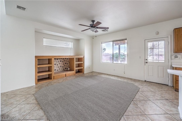 unfurnished living room with light tile patterned floors, visible vents, and a ceiling fan