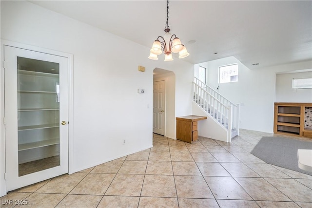 interior space featuring a chandelier, light tile patterned flooring, arched walkways, and stairs