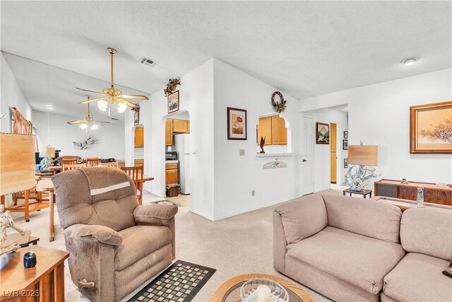 living room with lofted ceiling, ceiling fan, arched walkways, light carpet, and baseboards