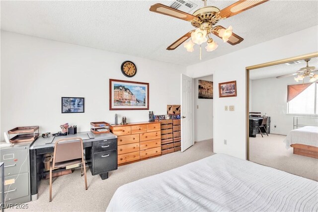 bedroom with light colored carpet, a desk, a textured ceiling, and a ceiling fan
