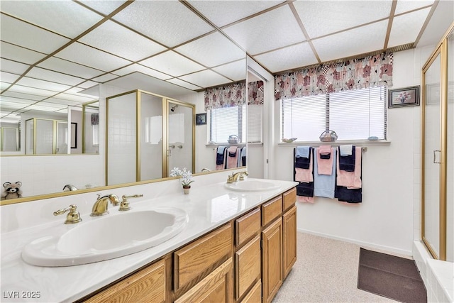 bathroom with a shower stall, double vanity, and a drop ceiling