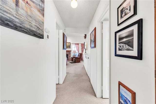 corridor with light colored carpet and a textured ceiling