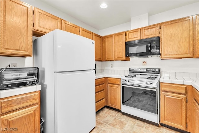 kitchen with white appliances, tile counters, and recessed lighting