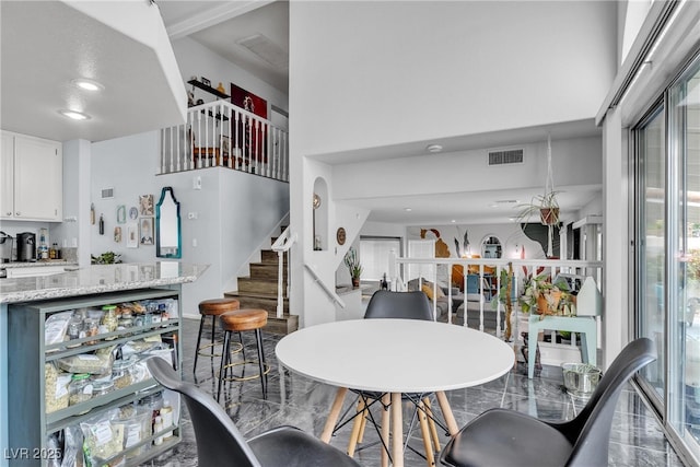 dining space featuring healthy amount of natural light, stairway, a towering ceiling, and recessed lighting