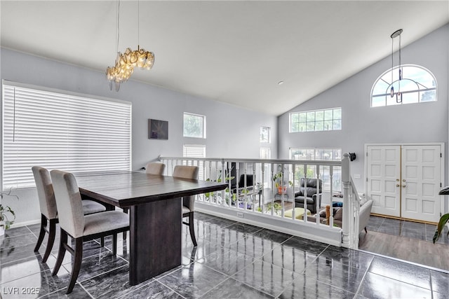 dining room with healthy amount of natural light, high vaulted ceiling, baseboards, and a chandelier