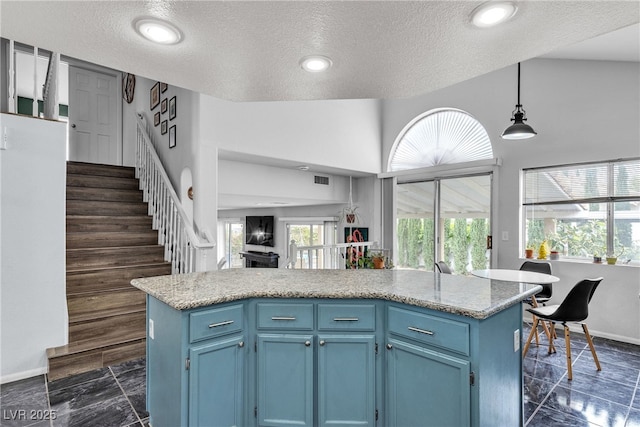 kitchen with blue cabinets, a textured ceiling, baseboards, pendant lighting, and plenty of natural light