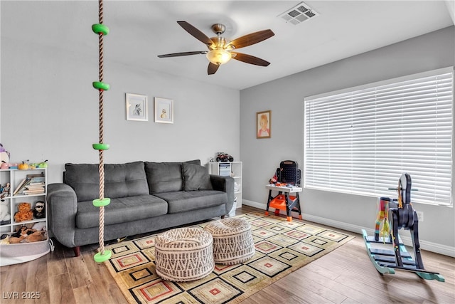 living area featuring a ceiling fan, wood finished floors, plenty of natural light, and baseboards