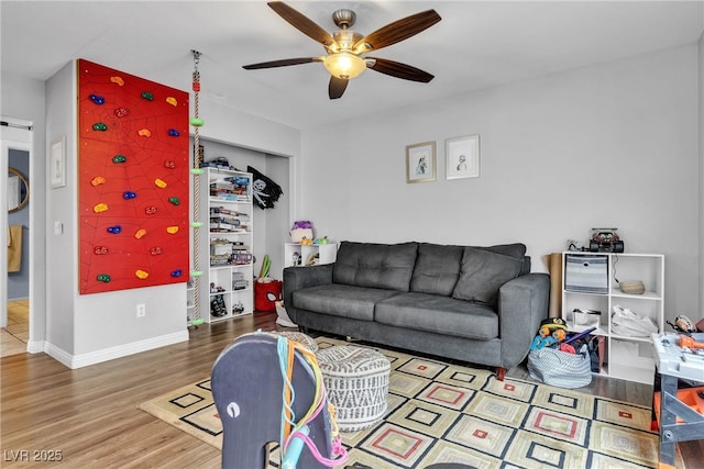 living area featuring wood finished floors, ceiling fan, and baseboards