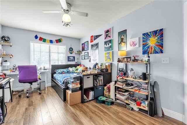 bedroom featuring wood finished floors, an office area, baseboards, and a ceiling fan