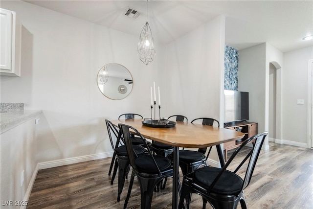 dining area with light wood finished floors, arched walkways, and baseboards